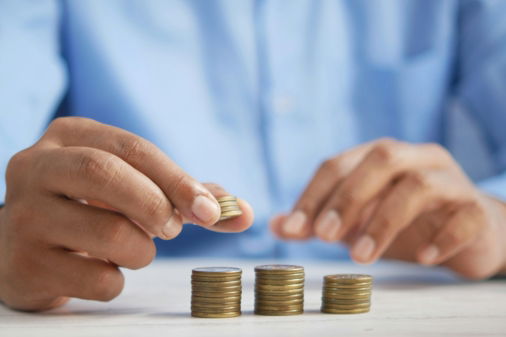 a-person-stacking-coins-on-top-of-a-table.jpg a person stacking coins on top of a table